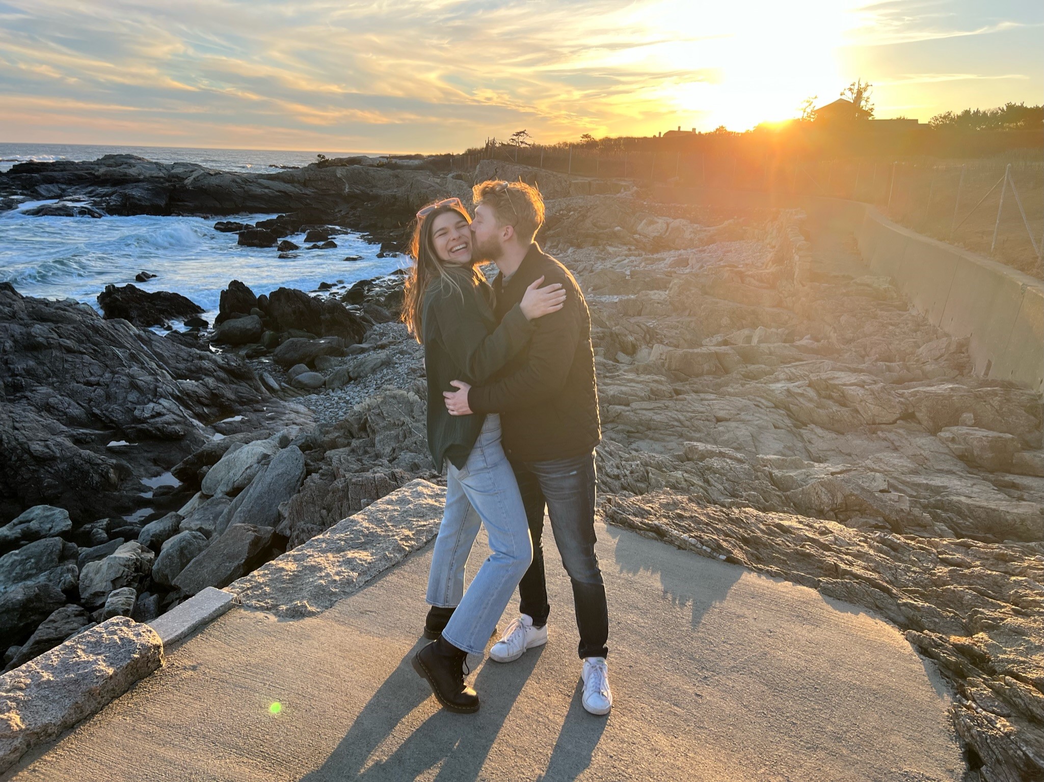 Canded photo in front of sunset on rocks next to beach.