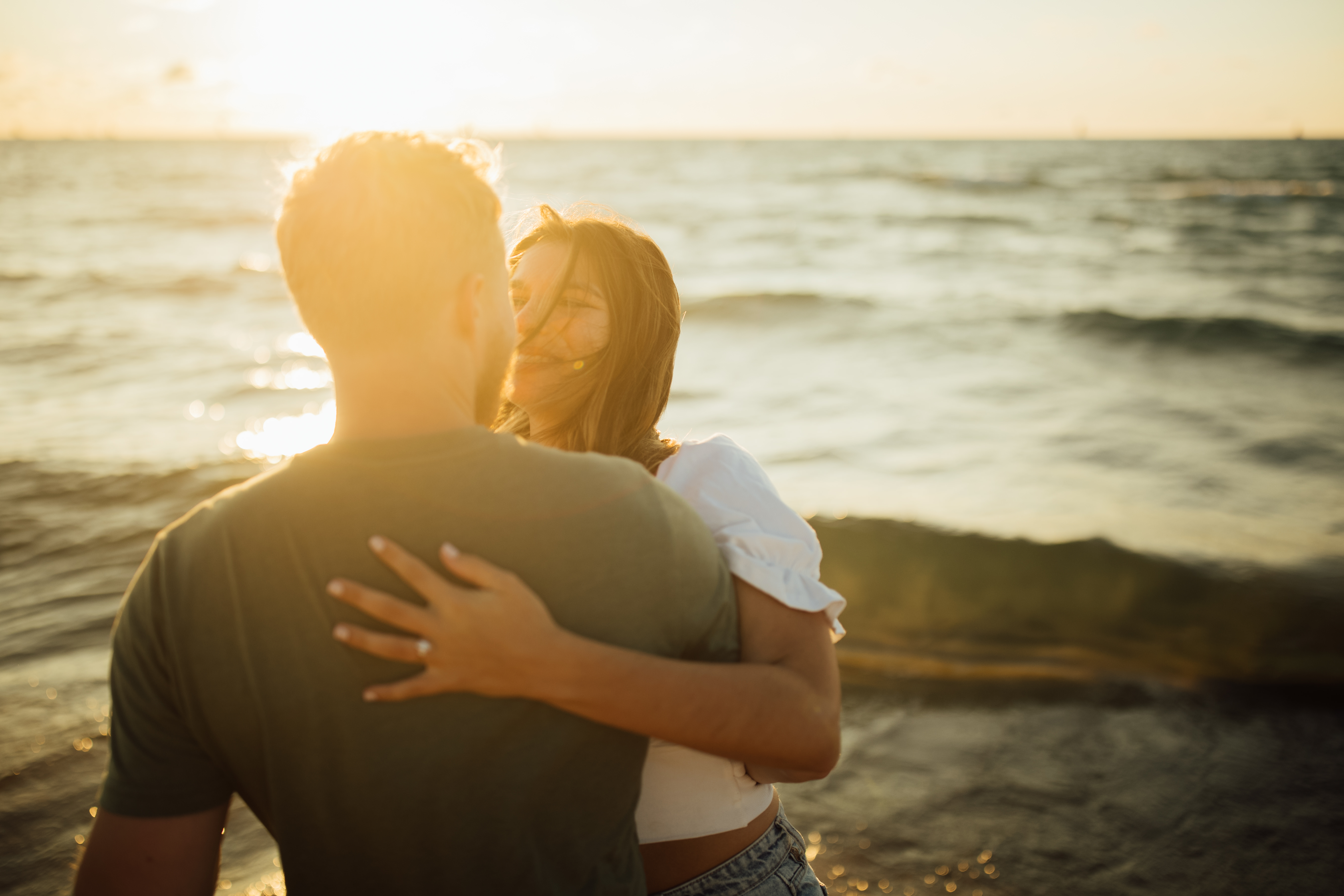 Enagement photo on the beach. A couple laughing.